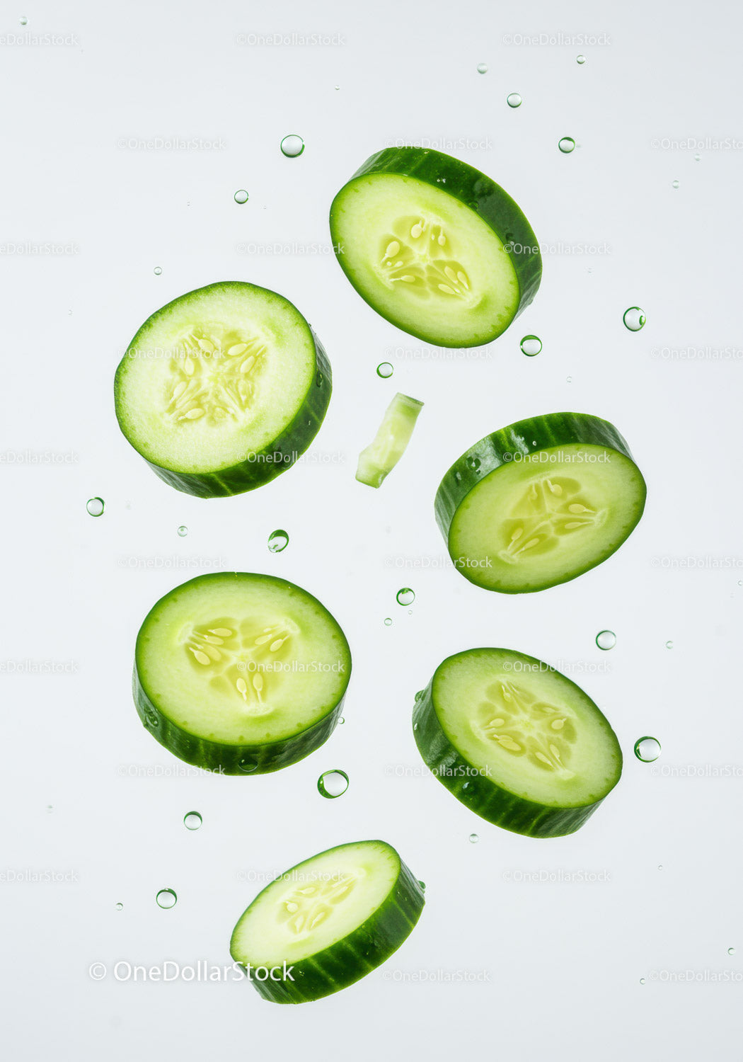 Fresh cucumber slices floating with water droplets