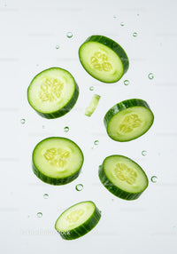 Fresh cucumber slices floating with water droplets