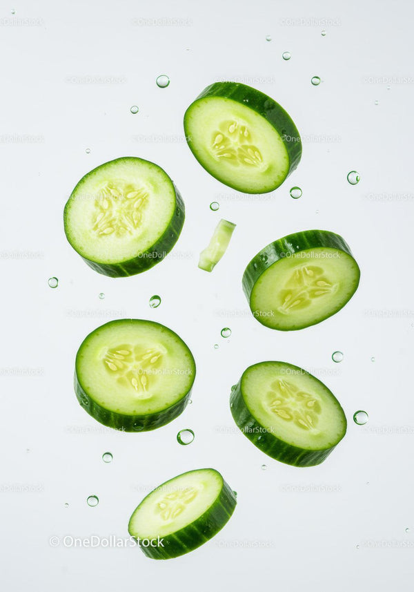 Fresh cucumber slices floating with water droplets