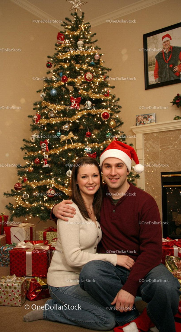 Couple Embracing by Decorated Christmas Tree with Gifts