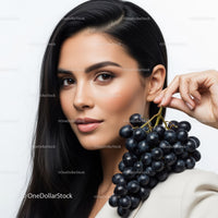 Elegant Woman Holding Black Grapes with Smooth Skin and Dark Hair