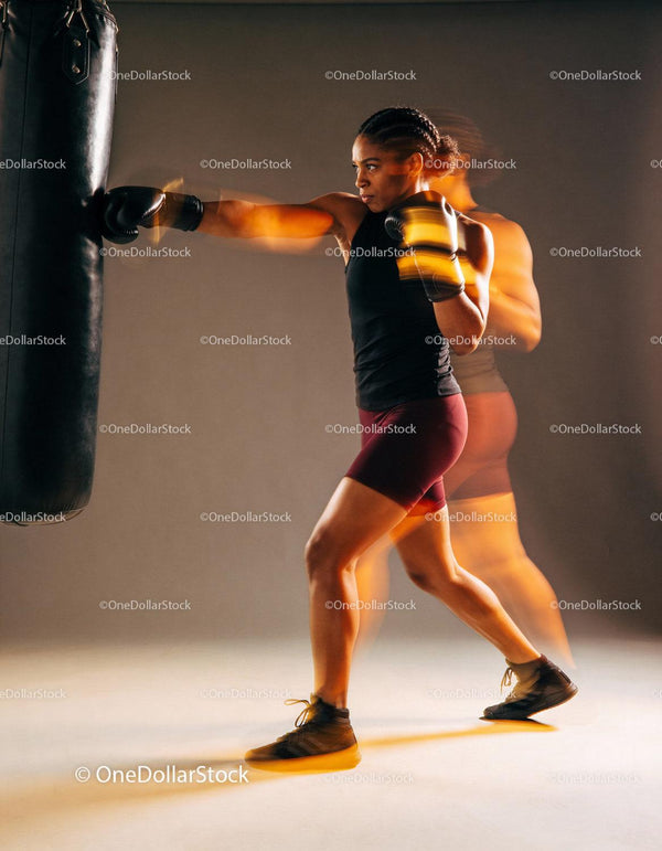 Focused woman training boxing punches on punching bag