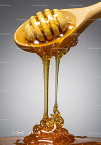 Golden honey dripping from wooden honey dipper