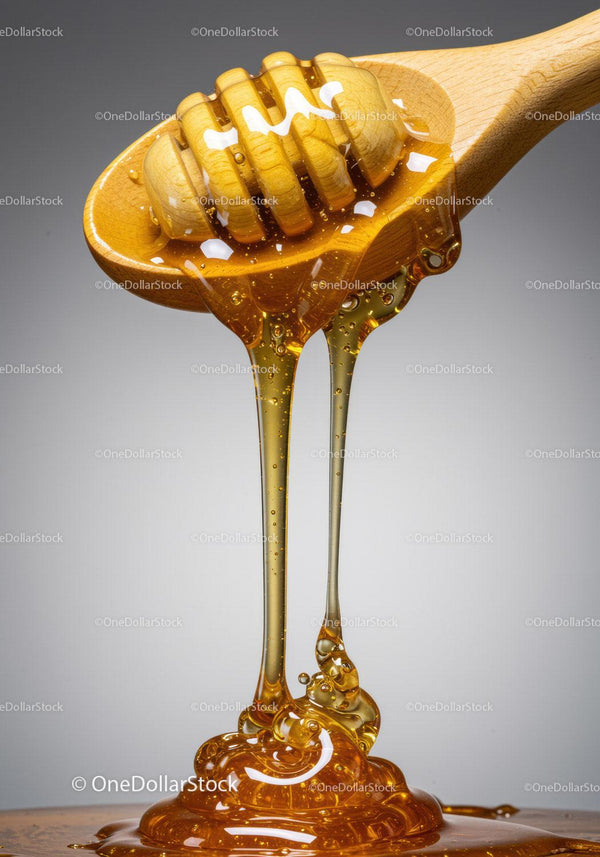 Golden honey dripping from wooden honey dipper