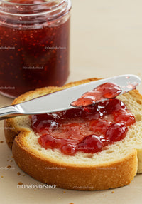 Spreading Red Berry Jam on Fresh Bread Slice