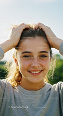 Young Woman Smiling Outdoors with Sunlight and Blue Sky