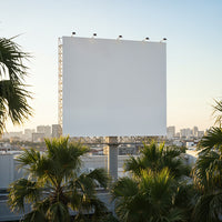 Blank billboard above city with palm trees at sunset
