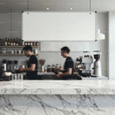 Minimalist coffee shop interior with marble counter and baristas