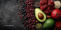 Fresh Organic Ingredients with Avocado and Pomegranate on Dark Surface