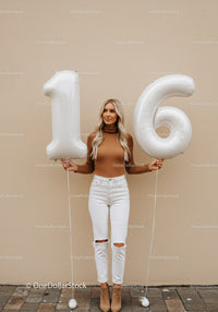 Young woman celebrating sixteenth birthday with balloons