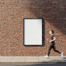 Person Running Past Blank Poster on Brick Wall
