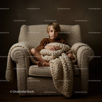 Thoughtful boy sitting wrapped in chunky knit blanket