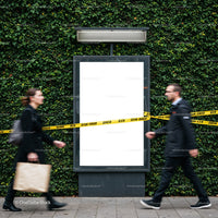 Two people walking past blank urban billboard with caution tape