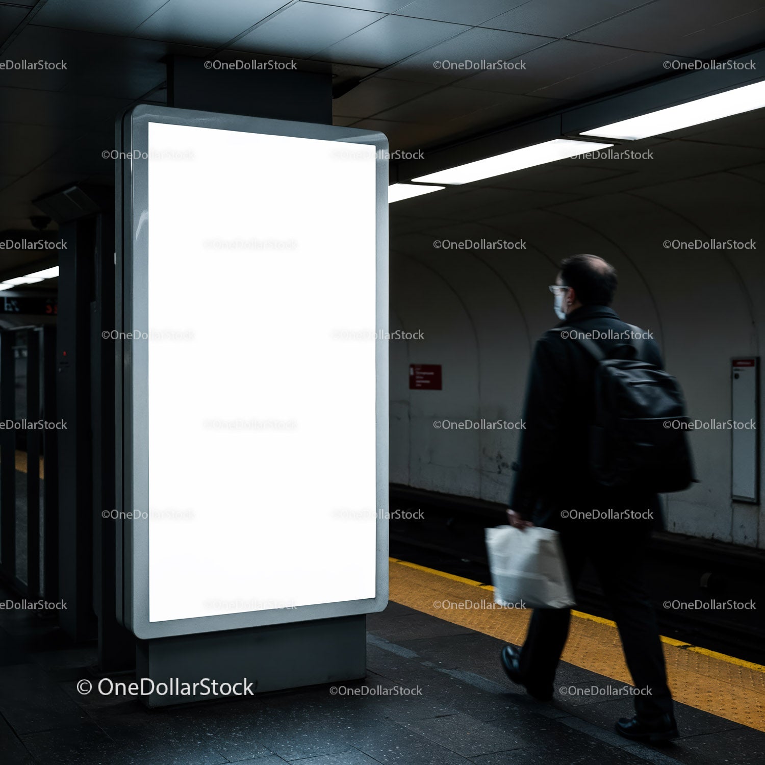 Pasażer przechodzący obok pustego, oświetlonego billboardu w metrze