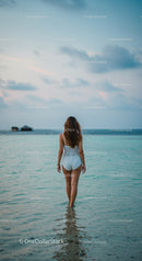 Woman Standing in Calm Ocean Water on a Scenic Beach at Dusk