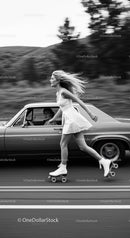 Young woman roller skating beside classic car on road