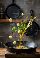 Pouring hot oil with garlic and herbs in black skillet