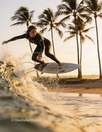 Female Surfer Jumping Over Wave Near Tropical Beach