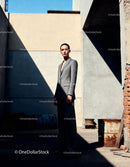 Confident woman in tailored gray suit in urban light and shadow