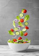 Fresh garden vegetables falling into white bowl salad