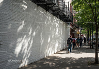 Urban Street Scene with White Brick Wall and Shaded Sidewalk