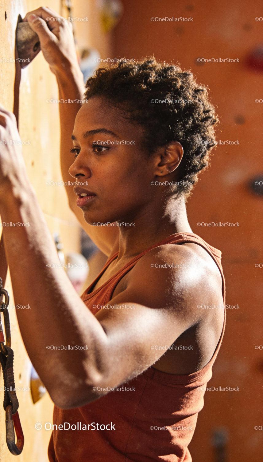 Focused woman climbing at indoor rock gym