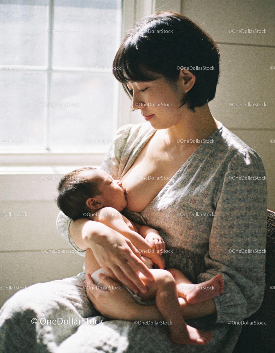 Mother gently breastfeeding newborn baby in soft natural light