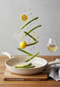 Fresh asparagus and lemon slices cooking in pan
