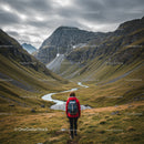 Scenic Mountain Valley with River and Hiker with Backpack