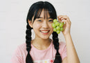 Joyful Girl Holding Fresh Green Grapes with Bright Smile