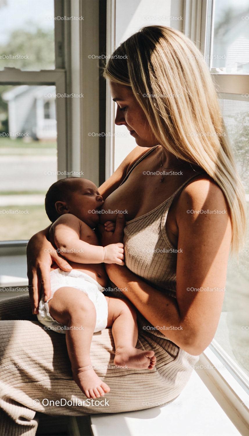 Mother lovingly breastfeeding her infant by the window