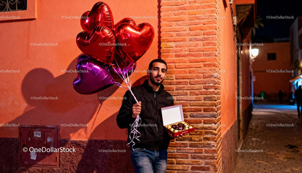 Man Holding Heart Balloons and Chocolates on Romantic Evening