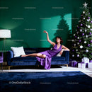 Elegant woman in purple dress lounging near Christmas tree