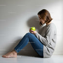 Young woman sitting on floor holding green apple