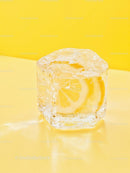 Lemon slice frozen inside a clear ice cube on yellow
