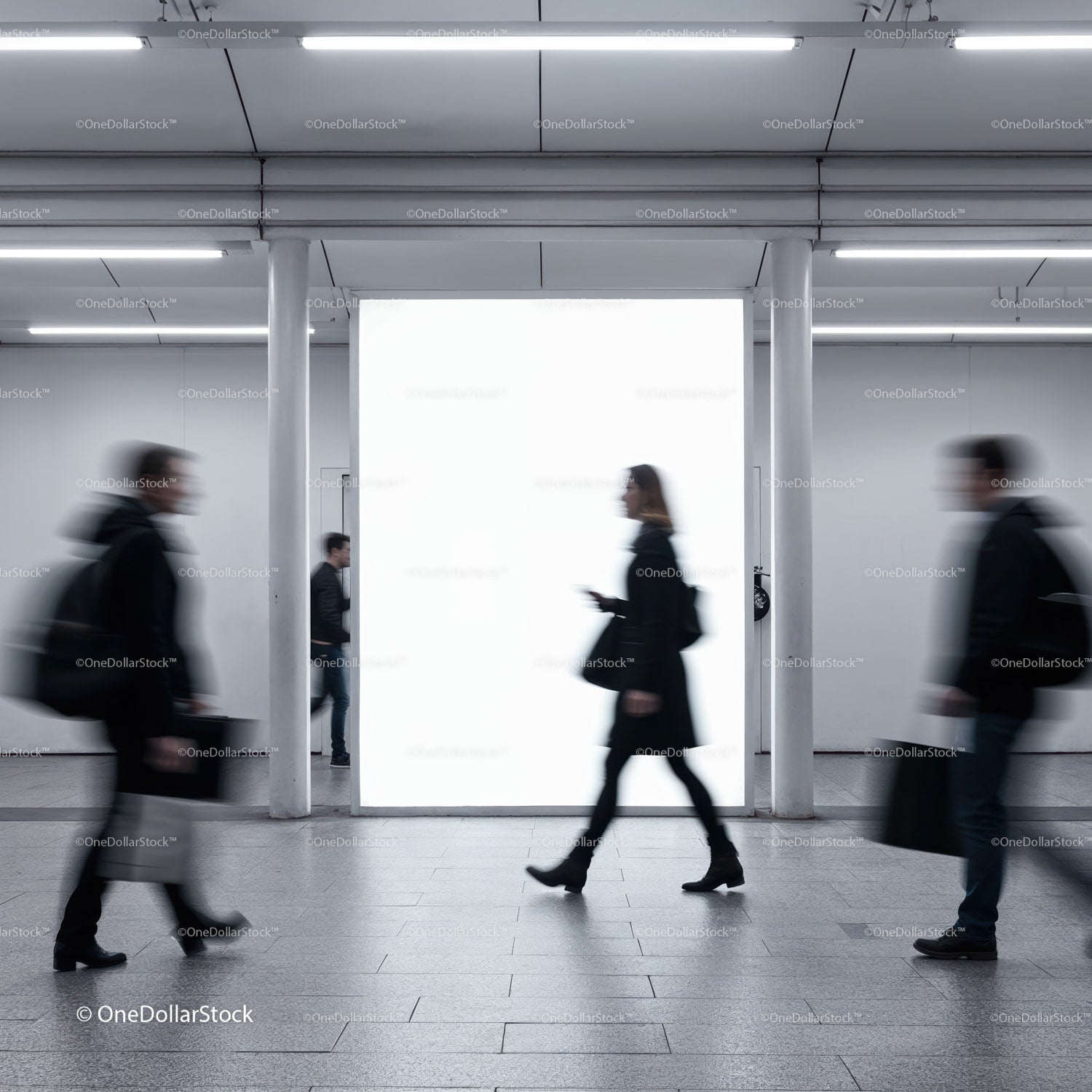 Blurry commuters walking past illuminated urban billboard