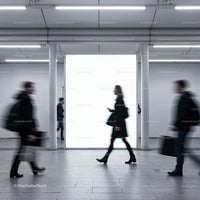 Blurry commuters walking past illuminated urban billboard