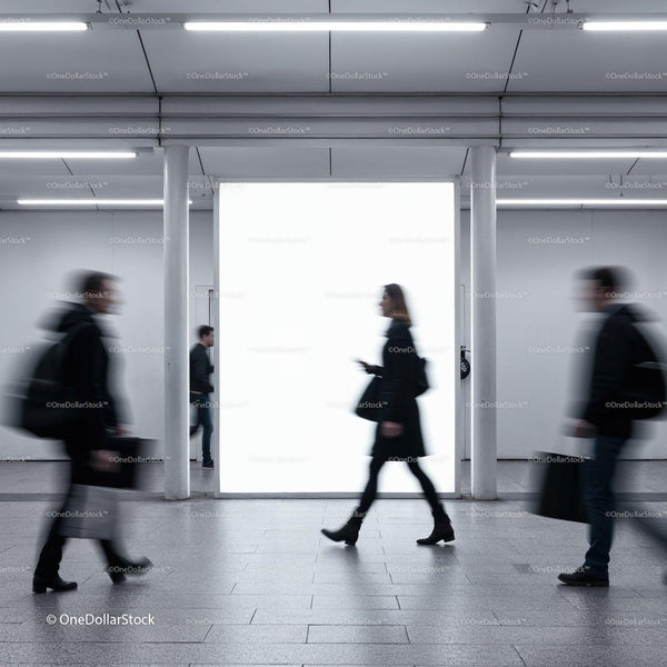 Blurry commuters walking past illuminated urban billboard JPG Mockup Image