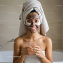 Young Woman with Facial Clay Mask and Towel Wrap Relaxing During Skincare Routine