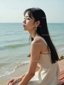 Elegant Woman in White Dress Sitting by Relaxing Seaside Landscape