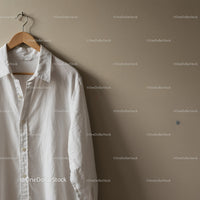 Casual white shirt hanging on wooden hanger indoors