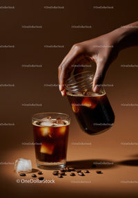 Hand Pouring Cold Brew Coffee Over Ice Cubes