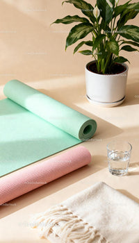 Rolled pastel yoga mats next to green houseplant and water