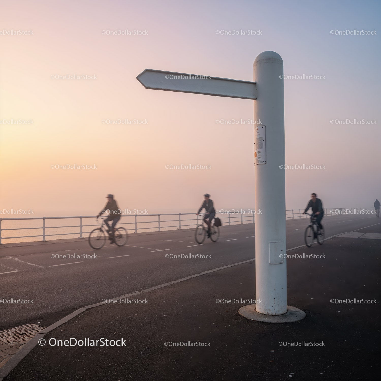Cyclists riding along foggy coastal promenade at dawn