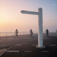 Cyclists riding along foggy coastal promenade at dawn
