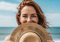 Smiling Woman Holding Straw Hat with Ocean in Background for Summer Lifestyle