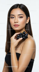 Elegant Woman Holding Black Grapes with Flawless Skin and Stylish Makeup