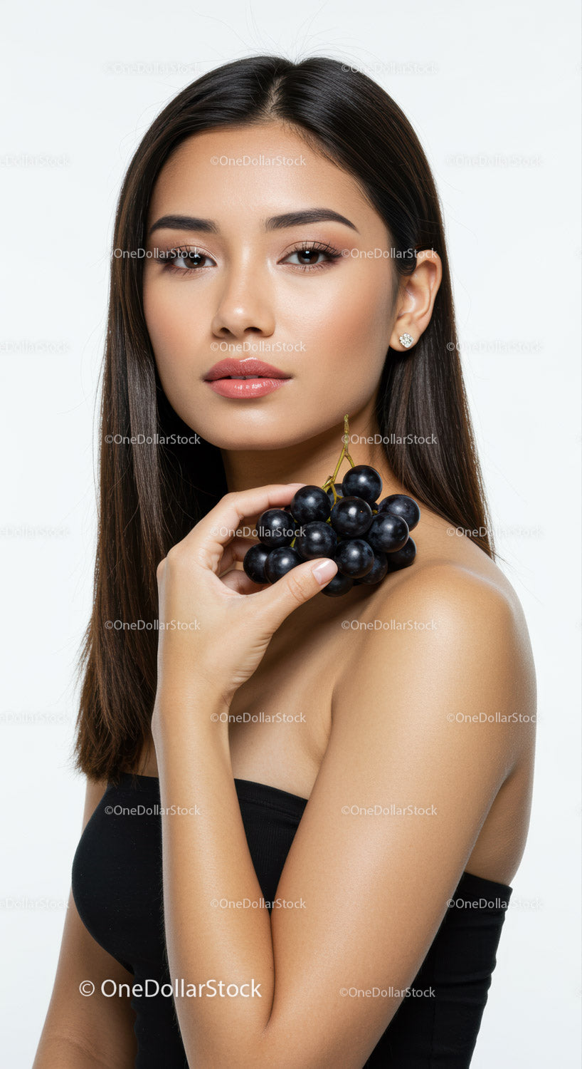 Elegant Woman Holding Black Grapes with Flawless Skin and Stylish Makeup