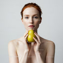 Portrait of a Woman with Red Hair Holding a Pear in a Minimalist Setting