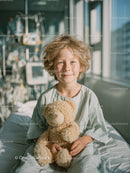 Happy Child with Teddy Bear in Bright Hospital Room